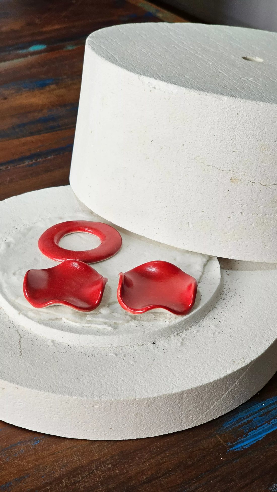 Joias autorais de cerâmica esmaltadas em vermelho sobre a base da mufla